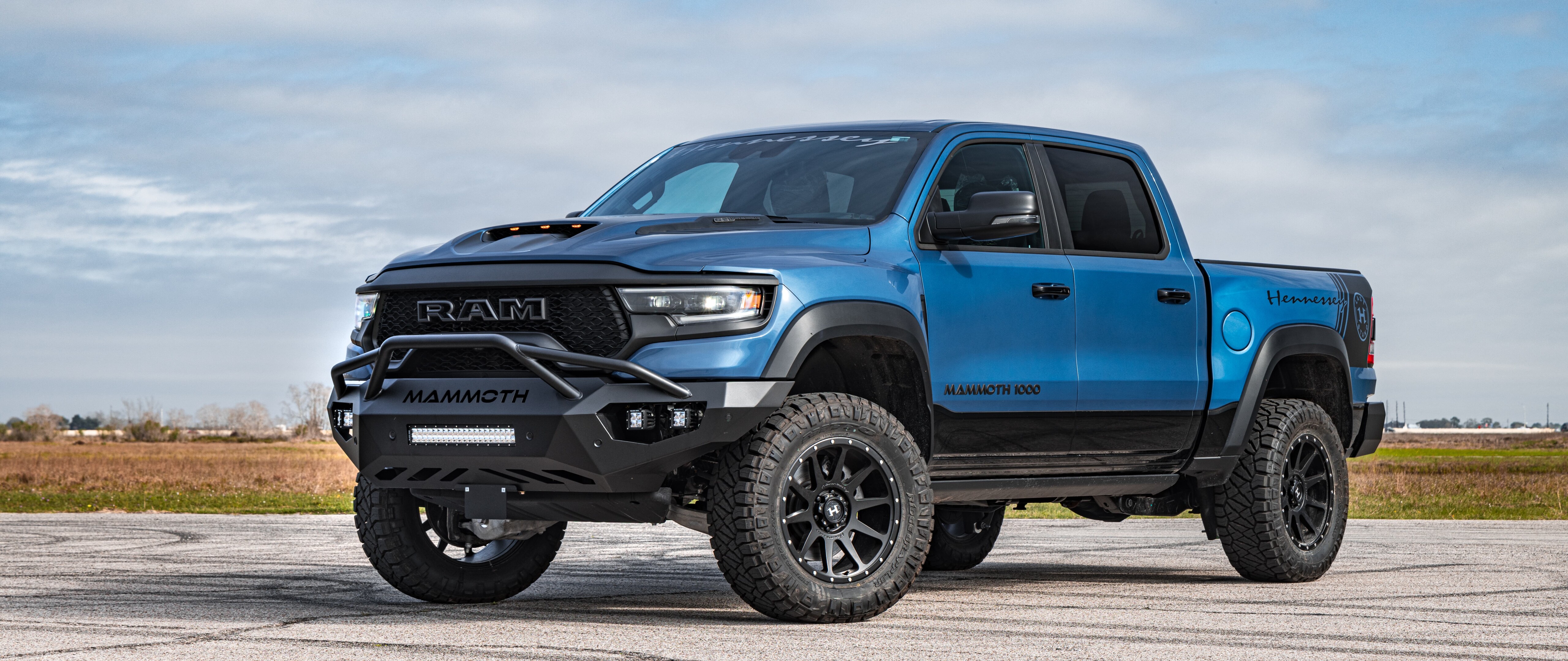 Un enorme camión Dodge Ram Hennessey Mammoth 1000, con una suspensión elevada, modificaciones agresivas para conducción todoterreno y una carrocería ensanchada.