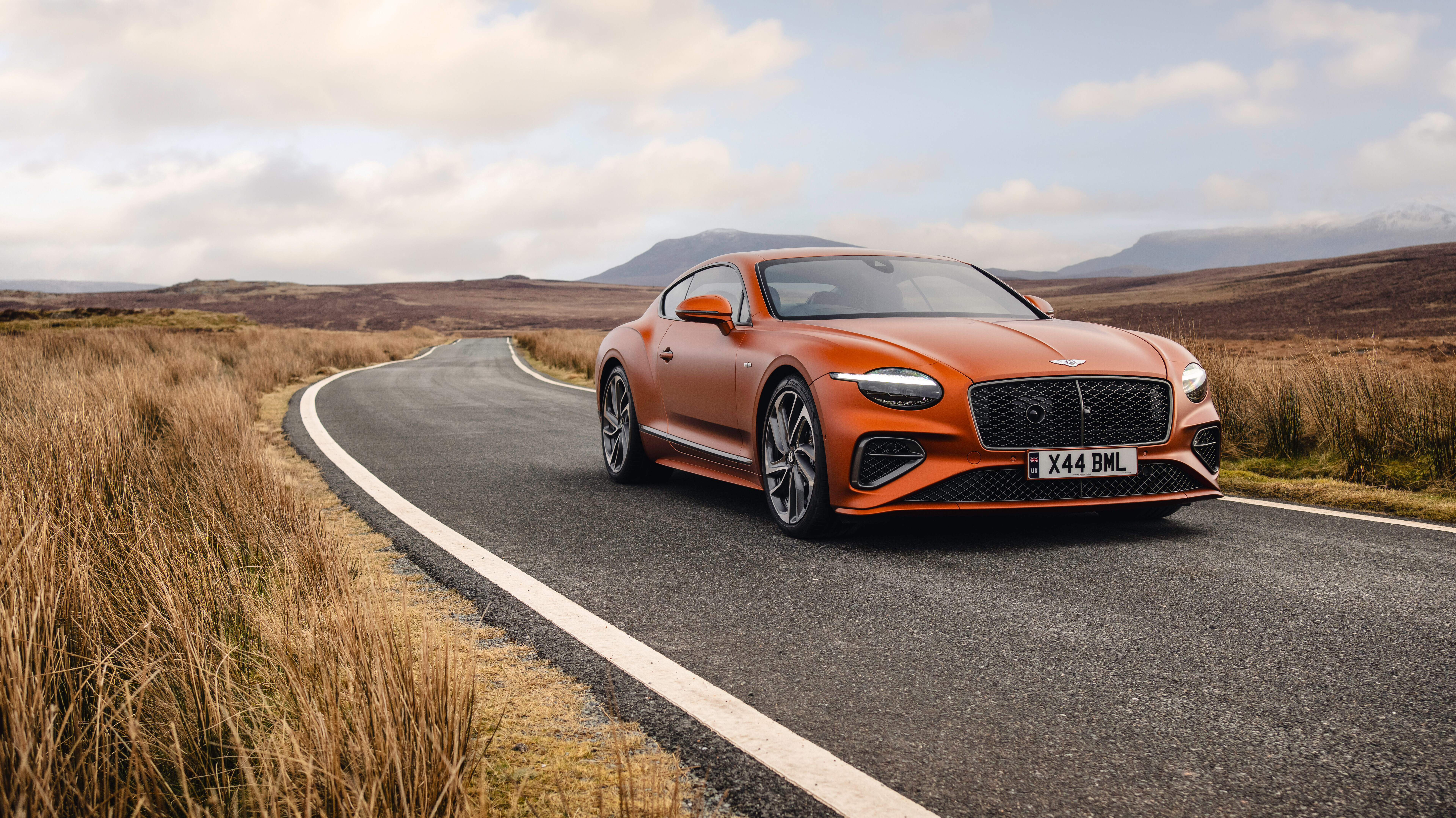 Un llamativo Bentley Continental GT Speed de color naranja que destaca por su lujoso diseño y su imponente presencia.