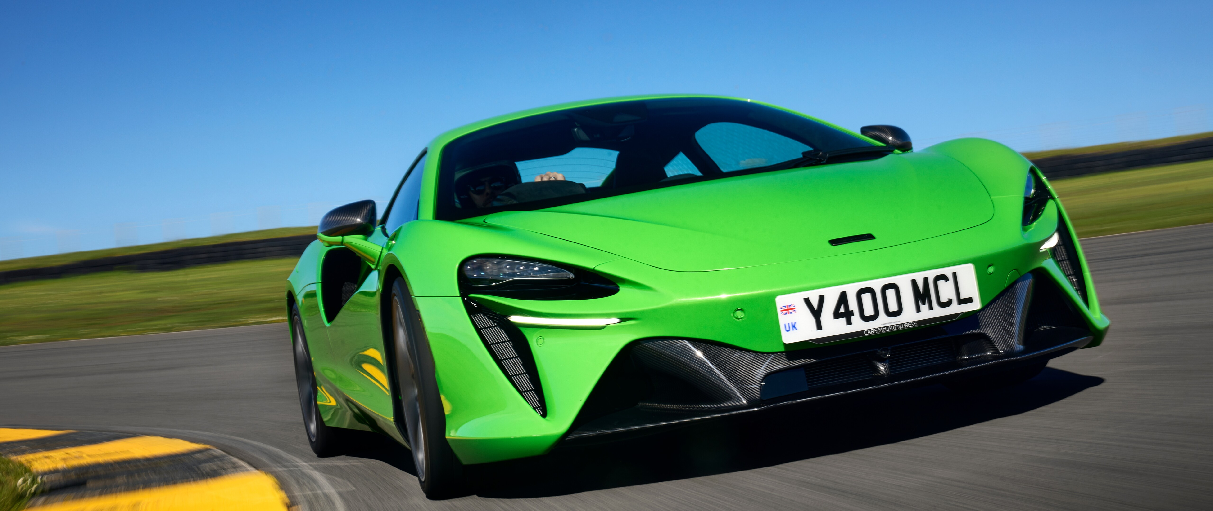 Un llamativo McLaren Artura de color verde brillante, un lujoso superdeportivo con líneas aerodinámicas y un acabado brillante.