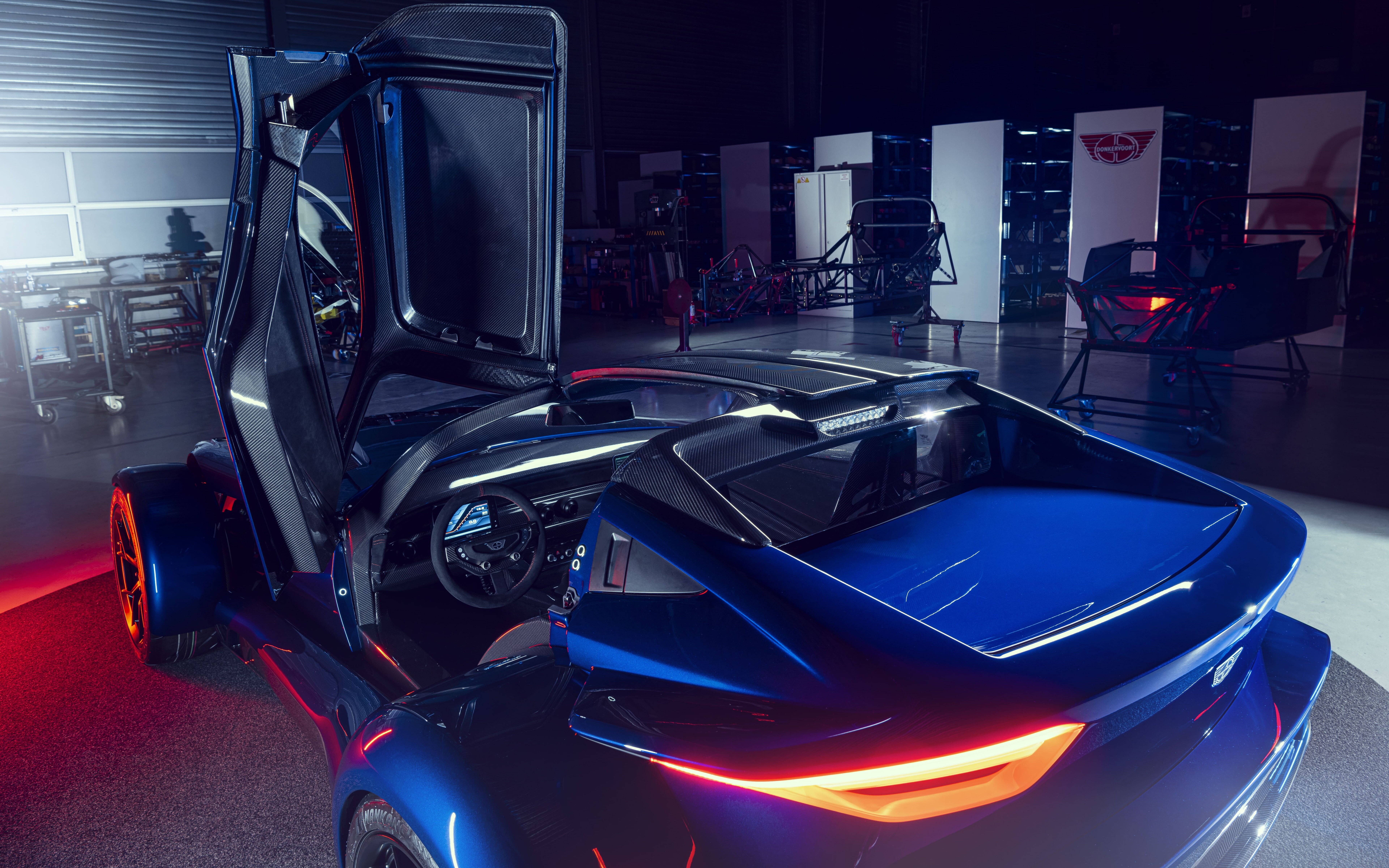 Un elegante coche deportivo de color plateado metálico que refleja la luz tenue de un estudio sobre un fondo oscuro.